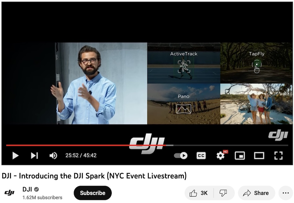 A split screen during a live streamed even on youtube shows a bearded male presenter gesturing on the left part of the screen and a quadrant made up of views from the drone camera on the right.